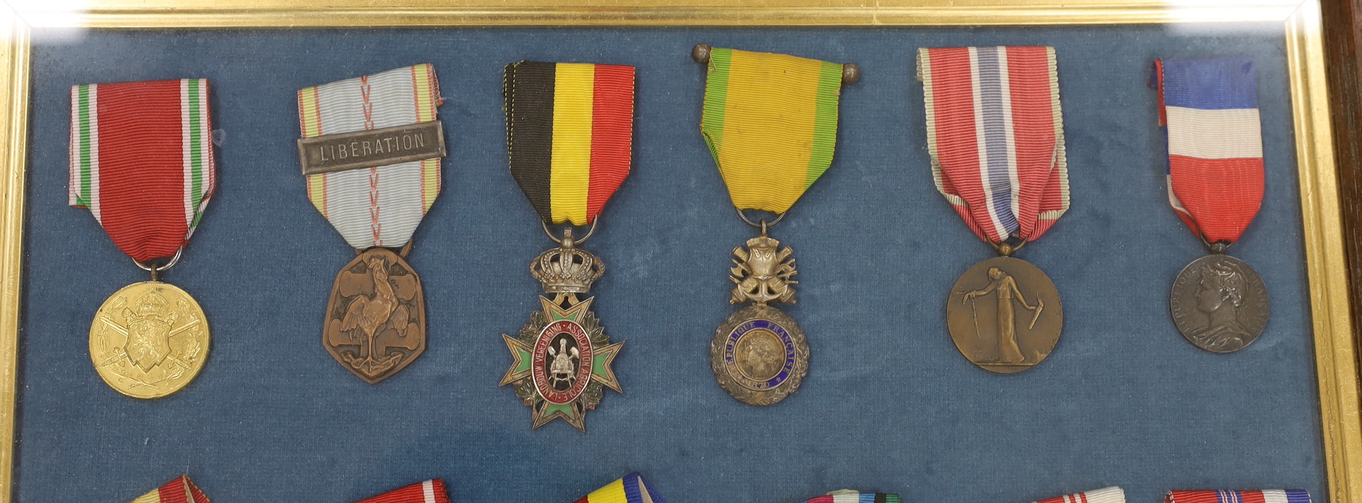 Twenty-seven medals and awards mounted in oak frames, including; French 1939-45 War Medal, Poland Lenino Cross 1943, Romanian Commemorative Medal, Belgium Red Cross Medal, etc. together with cloth shoulder titles for the